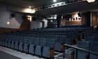 Interior de una sala de cine o auditorio con filas de butacas oscuras