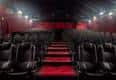 Vista interior de la sala de cine con butacas oscuras y alfombra roja