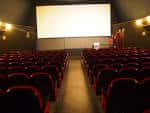 Interior de la sala de cine con butacas rojas y pantalla grande