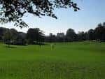 Vista soleada del gran campo abierto de Hove Park, rodeado de árboles