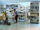 Interior de la sala de lectura de la Biblioteca Pública Jovellanos con estanterías y mesas