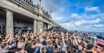Multitud en un evento diurno al aire libre frente a la fachada del edificio de Volks