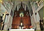 Interior de la parroquia mostrando el retablo principal de madera oscura y la nave