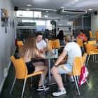 Zona de cafetería o encuentro con mesas y sillas naranjas