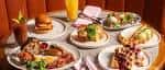 Mesa con una variedad de platos de brunch, incluyendo hamburguesa, gofres y cócteles, en el restaurante.