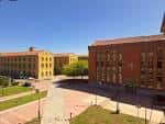 Vista exterior del Campus de El Milán, mostrando la plaza central y los edificios de ladrillo rojo y amarillo