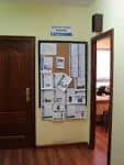 Tablón de anuncios informativo en el pasillo del Centro Cívico junto a una puerta de madera