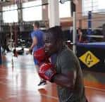 Primer plano de un boxeador entrenando con guantes rojos en el área de ring del gimnasio