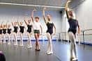 Grupo de jóvenes bailarines practicando en un estudio de danza con barras