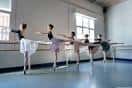 Estudiantes de ballet realizando ejercicios en la barra en un estudio bien iluminado