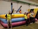 Participantes posando junto a un juego hinchable de justas en el interior del recinto