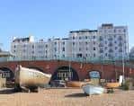 Vista diurna del hotel Old Ship desde la playa de Brighton, mostrando la fachada y los arcos de ladrillo en primer plano