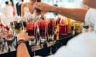 Primer plano de un camarero sirviendo múltiples cócteles rojos en la barra del bar