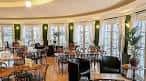 Interior del Rotunda Cafe Bar con grandes ventanales, cortinas blancas y mobiliario elegante