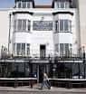 Vista frontal del edificio blanco de The Coach House con grandes ventanales