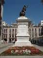 Estatua de Pedro Velarde en el centro de la plaza con la fachada del edificio al fondo