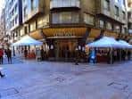 Vista exterior de la fachada de la librería en una esquina peatonal con carpas blancas