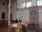 Detalle del presbiterio y el altar de la capilla con una gran cruz decorativa