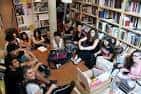 Interior de la librería Kaxilda con un grupo de personas participando en un encuentro cultural rodeados de estanterías de libros