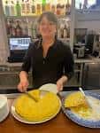 Personal del establecimiento sirviendo una tortilla de patatas en la barra
