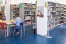 Interior de la biblioteca con estanterías de libros y puestos de lectura