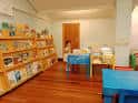 Sala de lectura infantil con suelos de madera y estanterías bajas accesibles