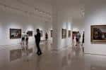 Interior de una de las salas de exposición con pinturas y visitantes