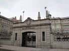 Entrada principal al colegio con portalón de piedra y verja