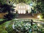 Vista nocturna de la casa palacio iluminada con estanque en primer plano