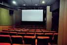 Interior de una sala de cine con filas de butacas y pantalla de proyección