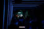 Vista del interior de la sala con iluminación de neón azul y escenario al fondo