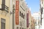 Exterior del teatro en una calle peatonal con banderolas distintivas
