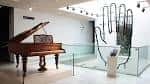 Espacio interior moderno del museo con un piano de cola clásico y luz natural