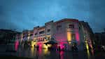 Fachada exterior del edificio La Perrera iluminada con luces de colores al anochecer
