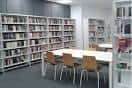 Interior de la biblioteca con amplias estanterías blancas y mesas de estudio