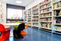 Zona de lectura con mobiliario de colores y estanterías de libros
