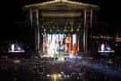 Gran escenario iluminado durante un concierto multitudinario al aire libre
