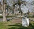 Sendero arbolado con palmeras y monumentos en el recinto del parque