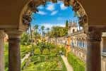 Vista panorámica de los jardines del Alcázar enmarcada por un arco de piedra