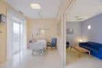 Interior de una habitación de hospital con zona de estar para pacientes y acompañantes