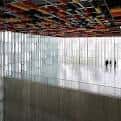 Gran sala diáfana con ventanales de suelo a techo y figuras humanas