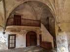 Interior de una estancia histórica con techos abovedados y balcón de madera