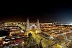 Panorámica nocturna del recinto ferial iluminado con la portada en el centro