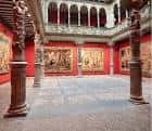 Detalle de la planta baja con columnas platerescas talladas y tapices históricos en las paredes