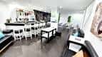 Interior del local con zona de barra, taburetes blancos y área de descanso