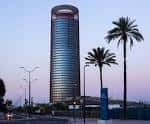 Perspectiva de la torre al atardecer con palmeras en el entorno urbano