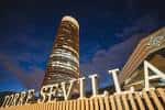 Fachada iluminada de la torre de noche junto al rótulo principal de acceso