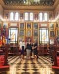 Interior del salón de plenos con decoración clásica, retratos y techos artesonados