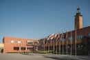 Fachada de edificio universitario con hileras de banderas y torre de ladrillo característica