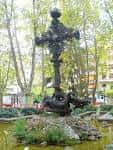 Monumento de la cruz rodeado de vegetación y jardines en la plaza